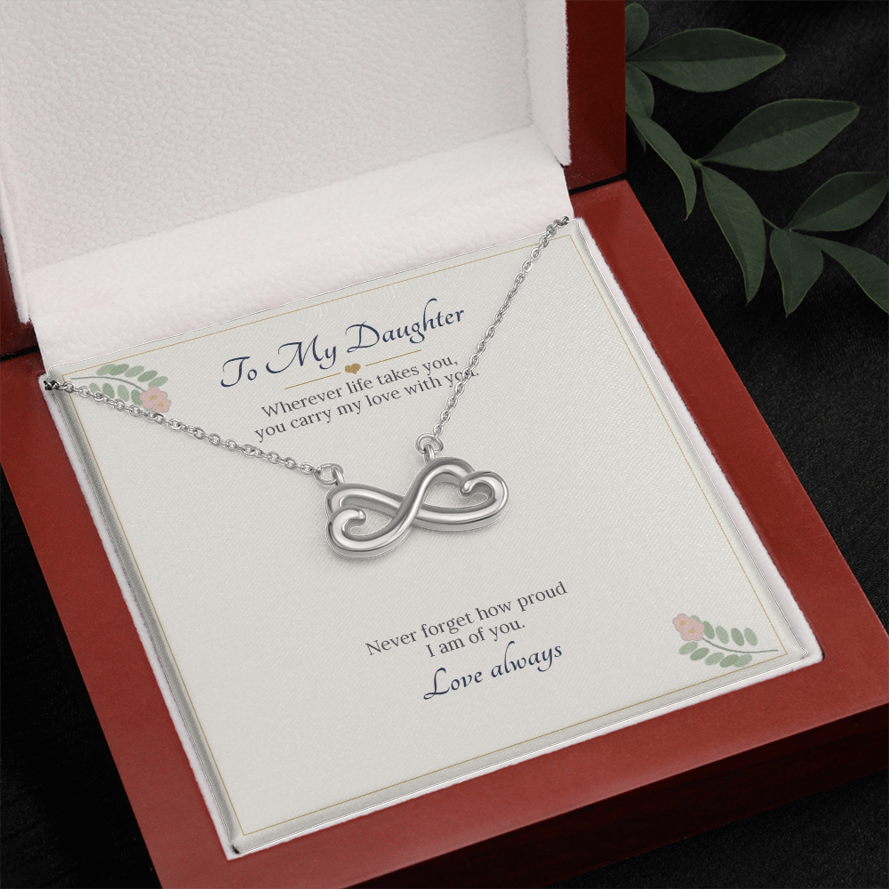 White gold finish infinity heart necklace on the To My Daughter card in an open wooden luxury box, seen from above with leaves beside it