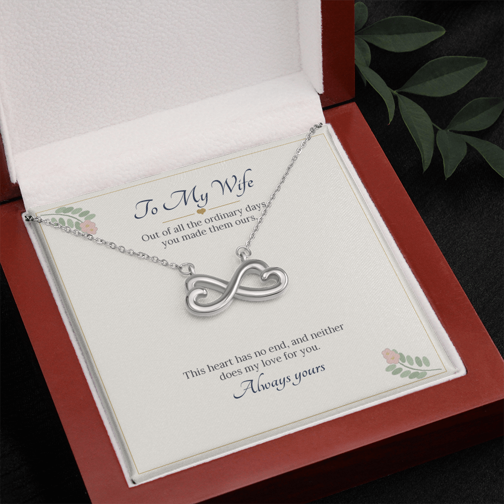 White gold finish infinity heart necklace on the To My Wife card in an open wooden luxury box, seen from above with leaves beside it