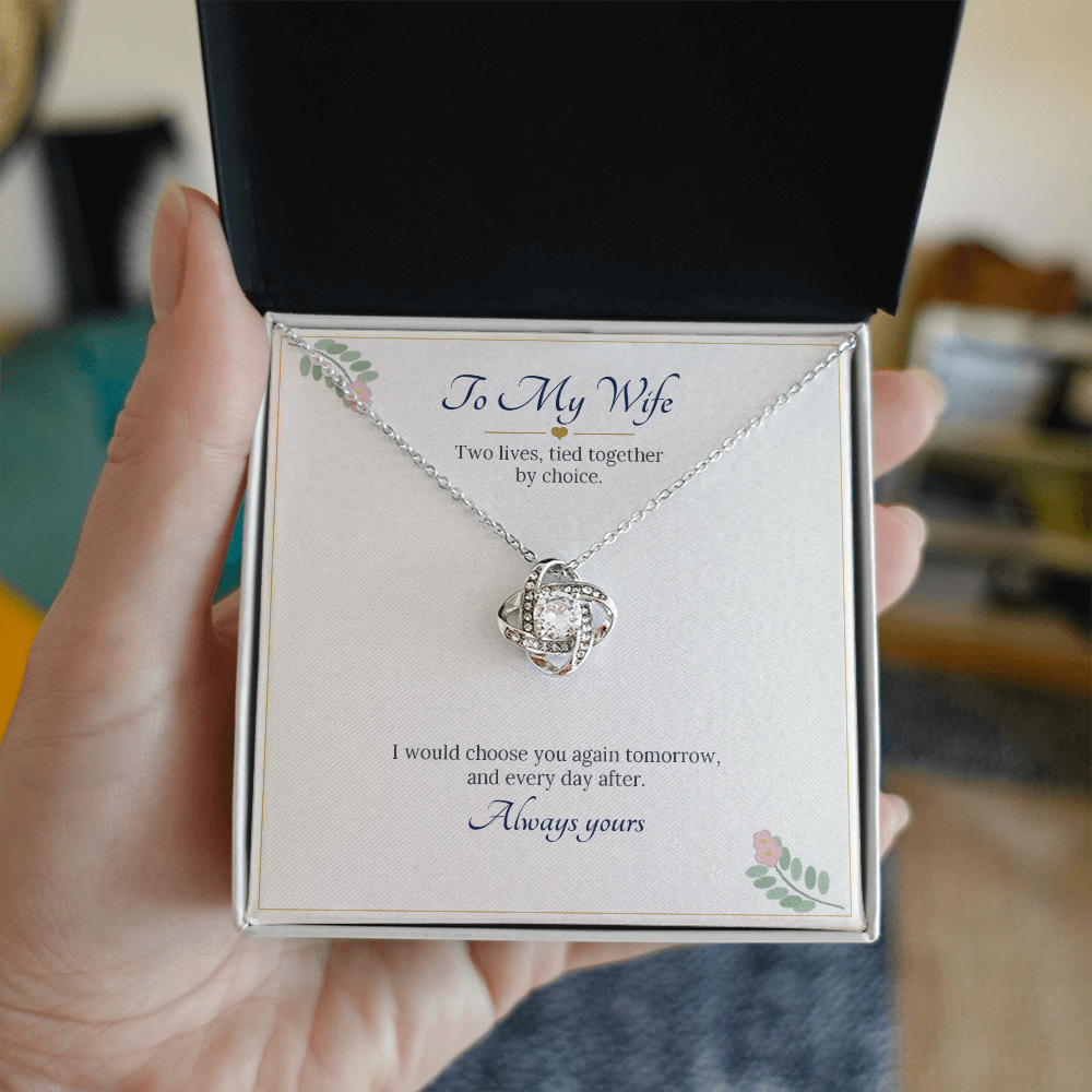 Hand holding the To My Wife message card with the white gold finish love knot necklace in its gift box