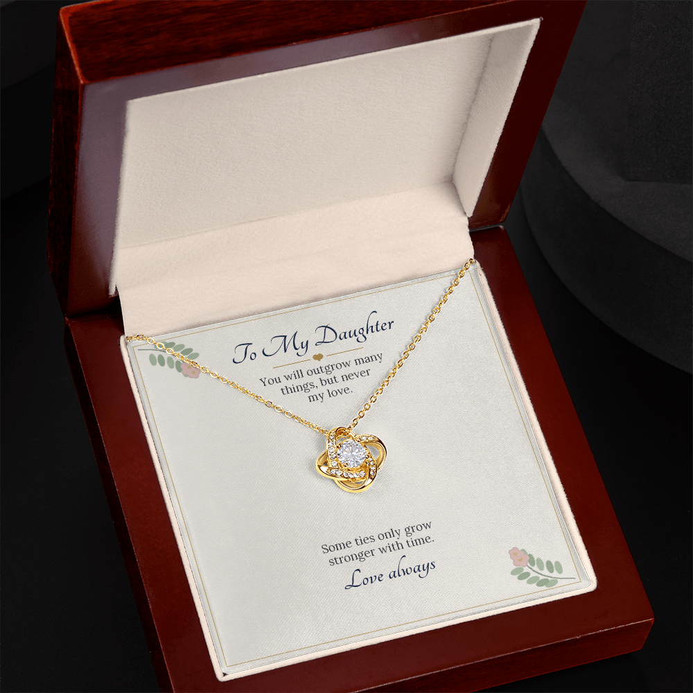 Yellow gold finish love knot necklace on the To My Daughter card in an open wooden luxury box on a dark background